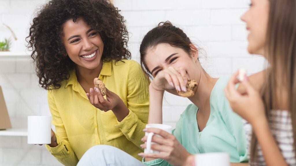 3 women laughing and drinking coffee