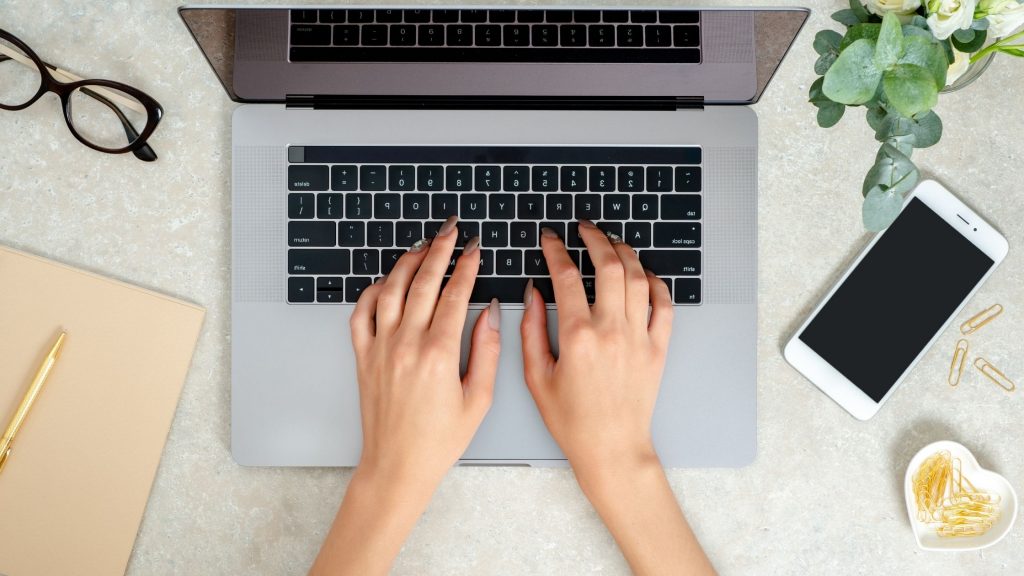 woman's hands typing on a laptop