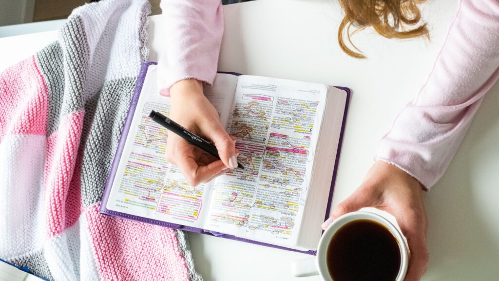 woman journaling in her Bible and drinking a cup of coffee