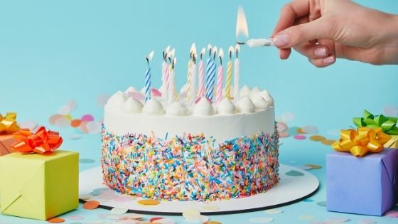 hand lighting candles on a birthday cake