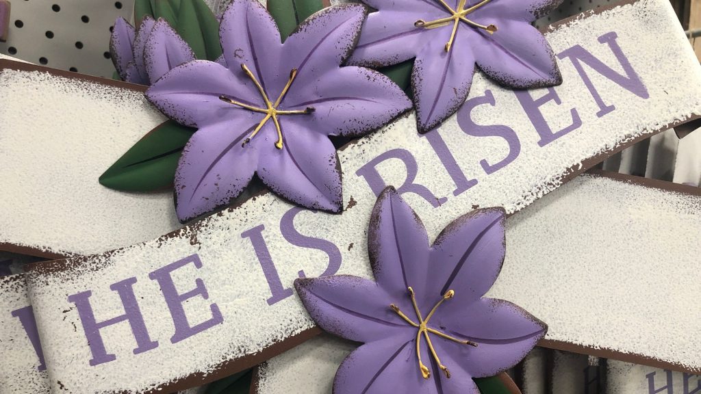 he is risen banner laid across purple flowers