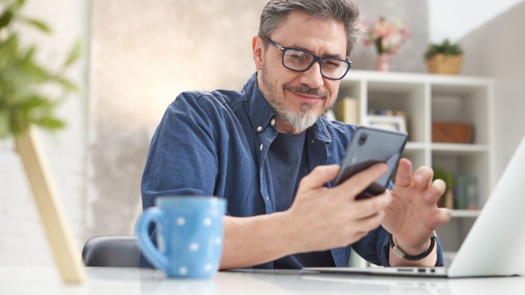 man drinking coffee and reading a devotional from his mobile phone