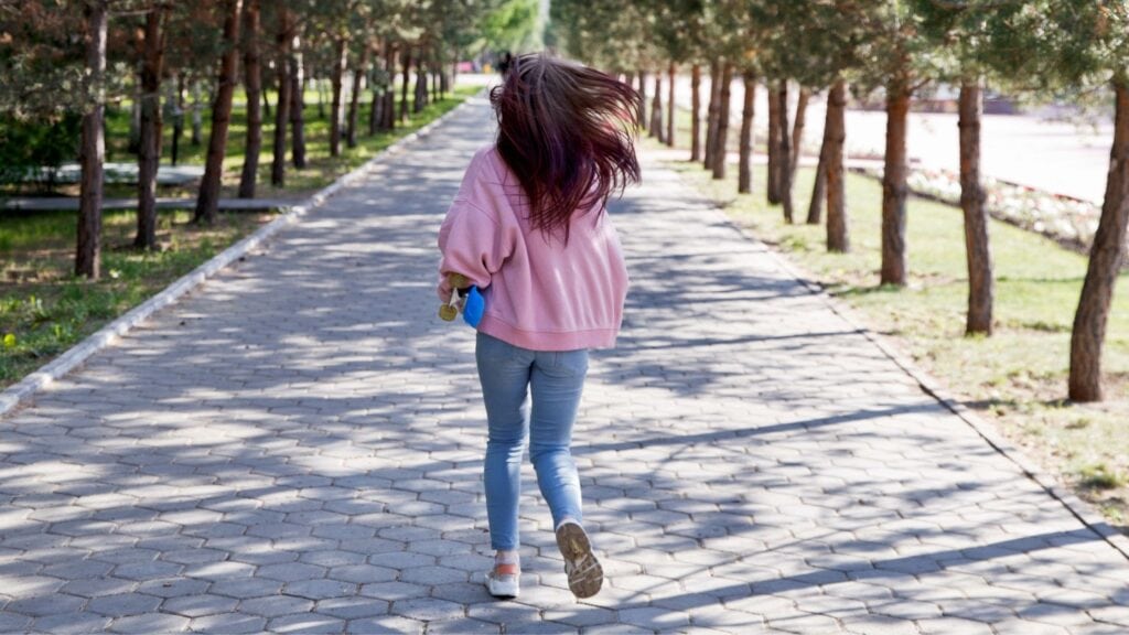 woman running away down a sidewalk
