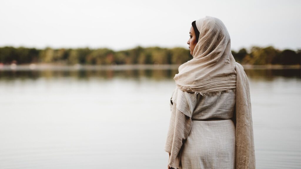 Biblical woman standing in a lake looking out over the water