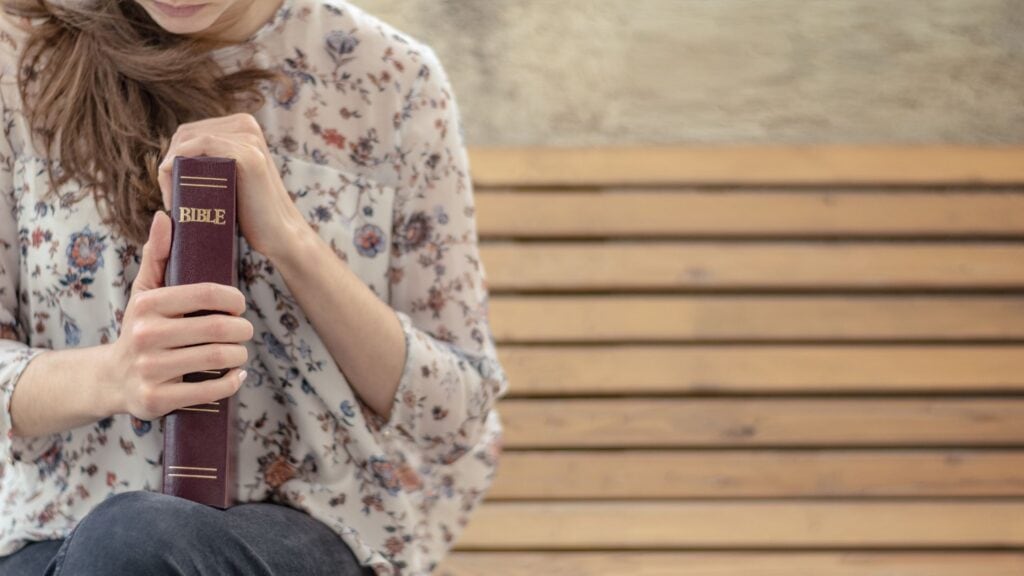 woman sitting on a bench holding her Bible