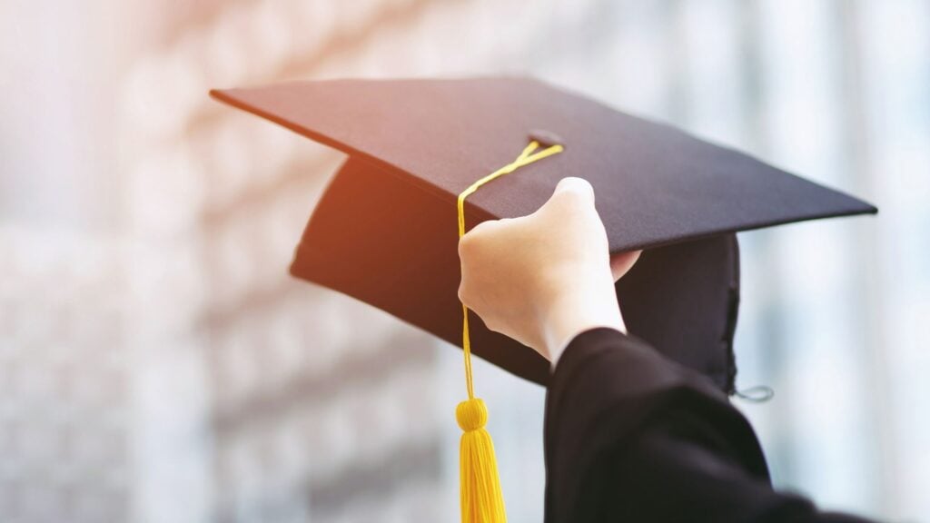 a person's hand holding up a graduation cap