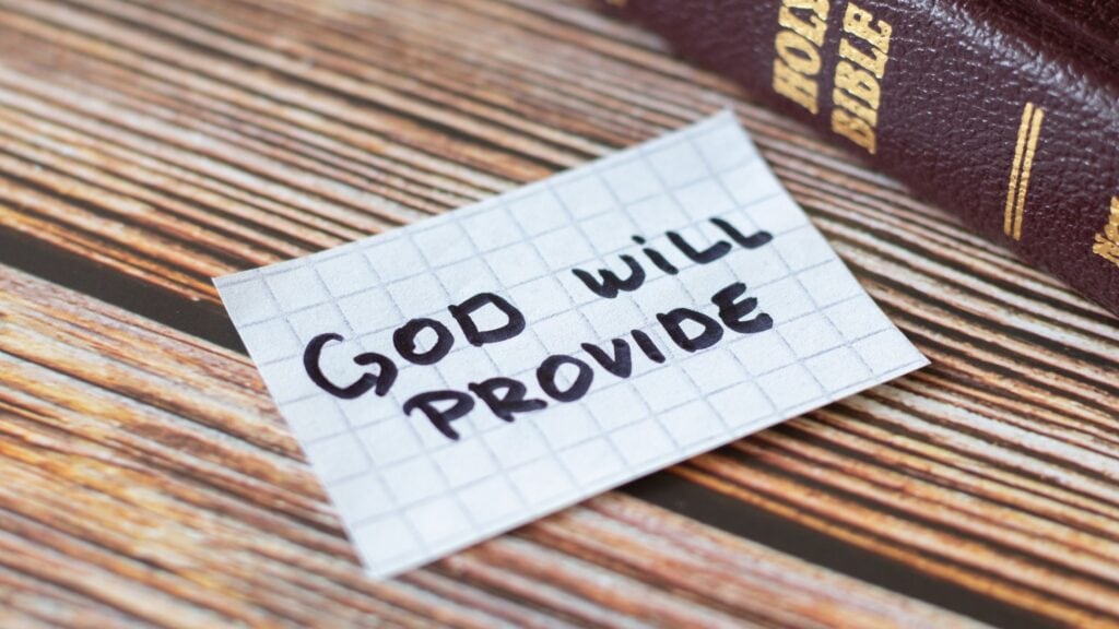 God Will Provide written on a piece of paper next to a Bible