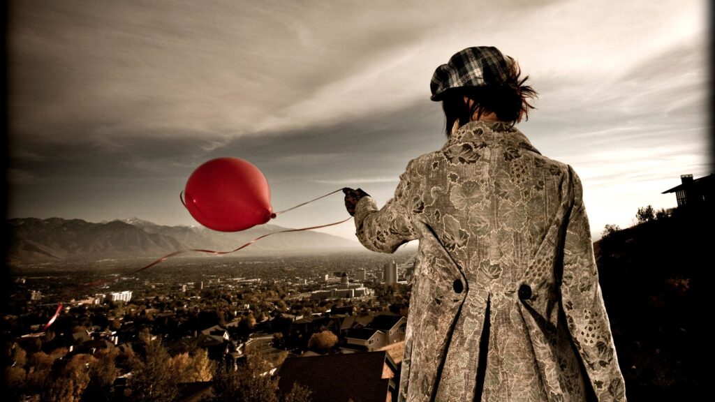 rear view of a woman letting go of a red balloon