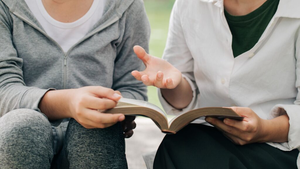 two people sitting together reading the Bible