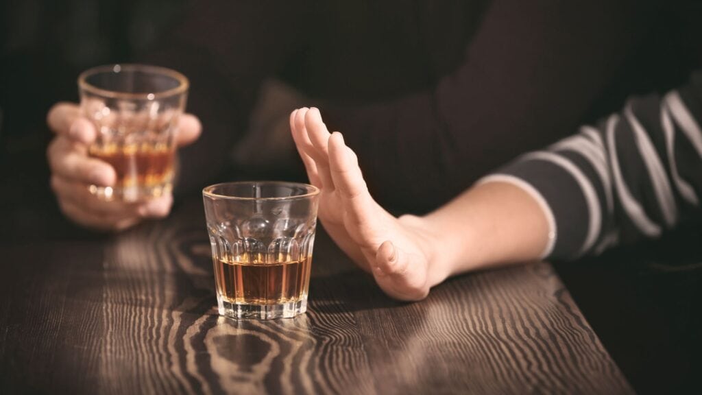a hand signaling that it doesn't want the alcoholic drink being offered