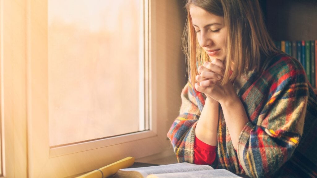 woman sitting by the window praying