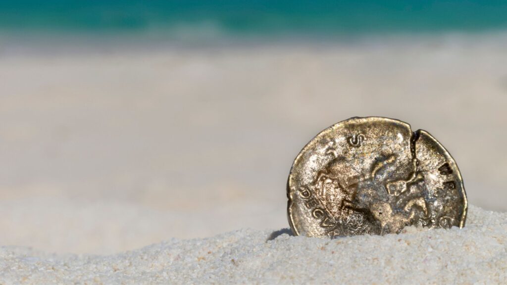 a single coin sitting upright in the sand